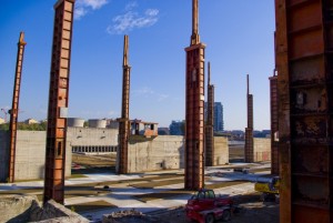 I pilastri dei capannoni dell’acciaieria durante i lavori per la realizzazione del parco; sullo sfondo il muro del parco rottami con la cabina di manovra e l’edificio per il trattamento acque. Fotografia Comitato Parco Dora, ottobre 2010.