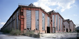 Il fronte dei capannoni dei laminatoi, con i caratteristici pilastri rossi in acciaio. Fotografia Filippo Gallino per la Città di Torino, aprile 2000.