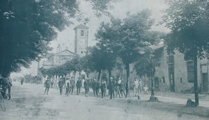 Foto degli inizi del Novecento che mostra quella che attualmente è via Passo Buole; dietro gli alberi si intravede la cascina Juva e sullo sfondo si vede la chiesa parrochiale.